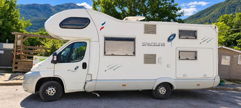Camping-car stationné sur un emplacement du camping, avec les montagnes de Castellane en arrière-plan