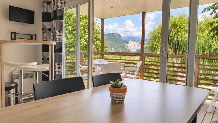 Salon lumineux d’un mobil-home du camping, avec terrasse et vue sur les montagnes de Castellane